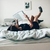 A photo of a woman reading a book while lying in bed